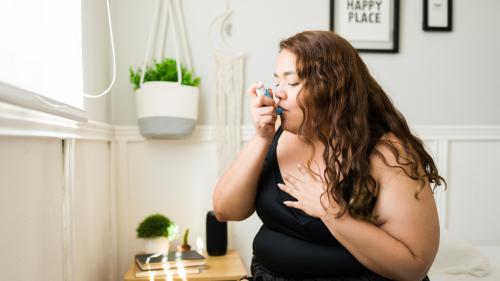 Woman uses asthma inhaler.