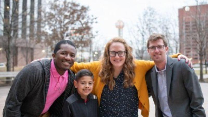 Four people in a city, smiling