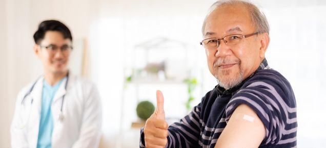 Older man gives thumbs up while showing off vaccine injection site.