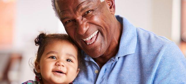 Older man smiles with baby girl.
