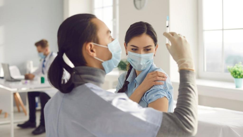 Medical professional giving shot to woman in mask