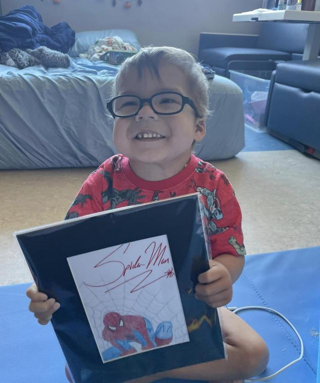 Young boy smiling with a picture of Spiderman