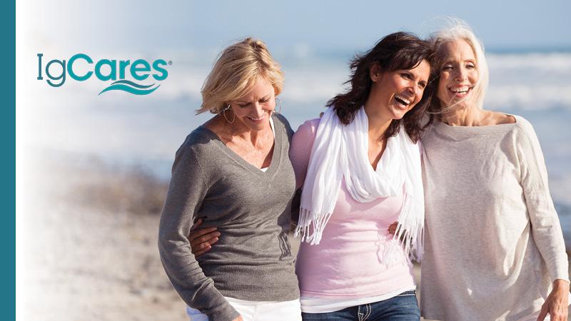 three women walking on beach with arms around each other.