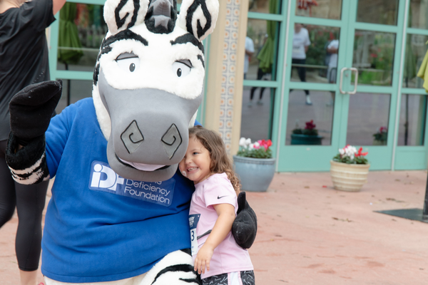 Small girl hugging Zebra mascot. 