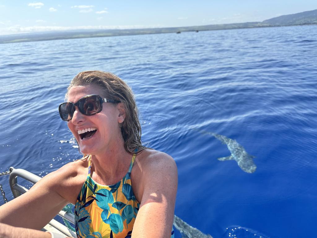 Stacy Ahearn riding in a boat with a shark in the water nearby