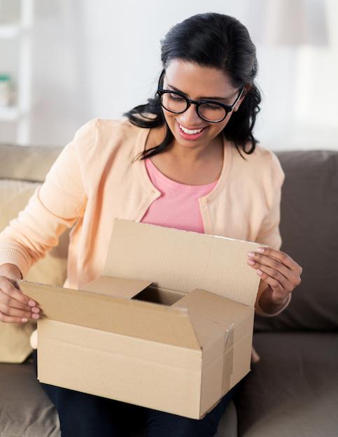 Woman with glasses opening a brown shipping box.