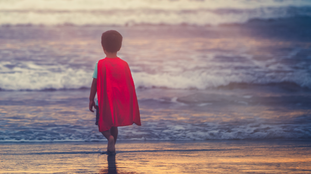 little boy in cape looking at the ocean