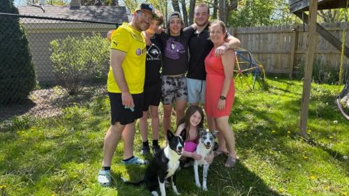 Savino family posing in a backyard with their two dogs.
