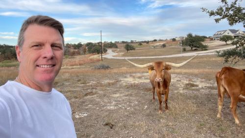 Scott Berry takes a selfie next to two longhorns.