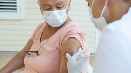 Older woman receives vaccine in the upper arm.