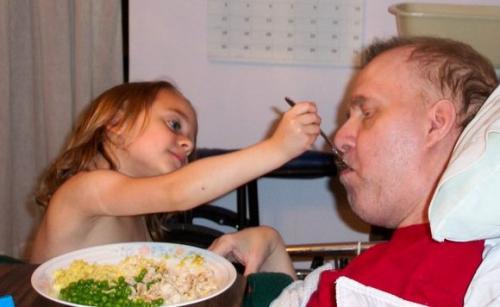 Taylor Kane feeds her father John Kane, diagnosed with adrenoleukodystrophy (ALD), which affected his physical and cognitive functioning.