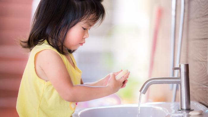 Little girl washing her hands with soap and water.