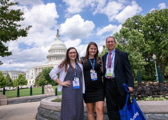 Three individuals standing in front of the United States Capitol. 