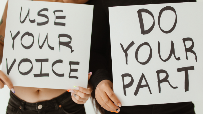 People holding "Use your voice" and "Do your part" signs.