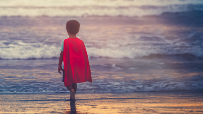 little boy in cape looking at the ocean