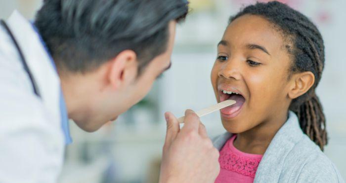 child at doctor receiving tongue depressor